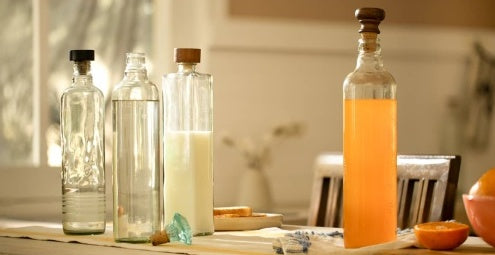 Shopi Vella glass water bottle with ceramic stopper and three other clear glass storage bottles on table