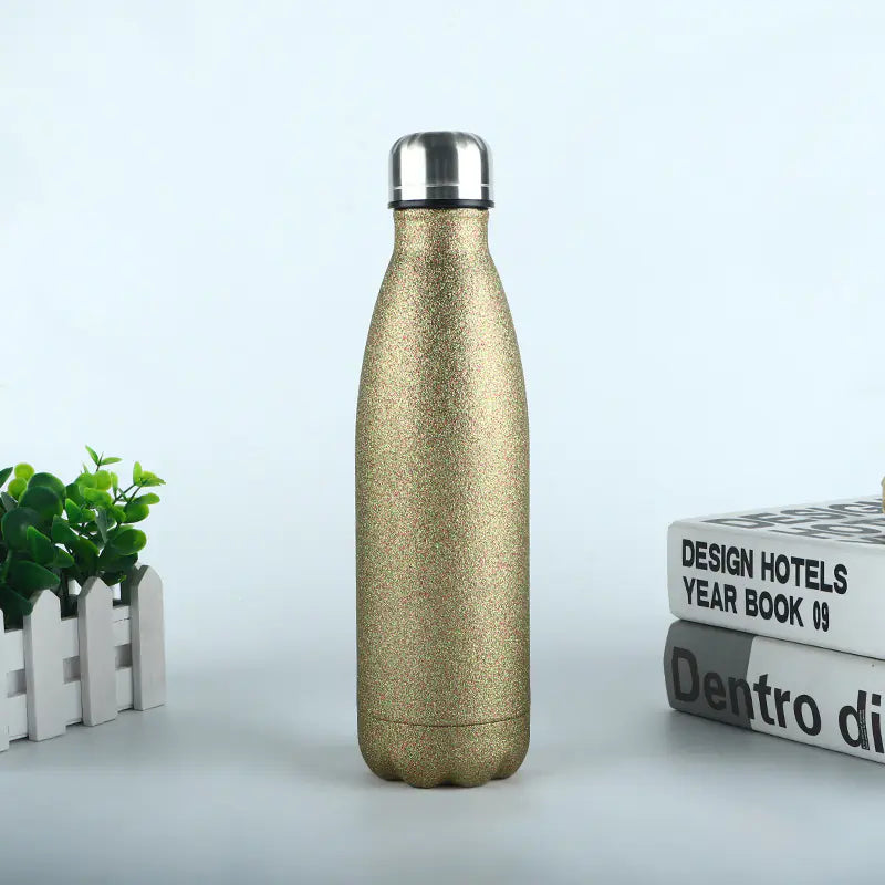 Gold glitter durable metal sports bottle for hydration with silver cap on white surface