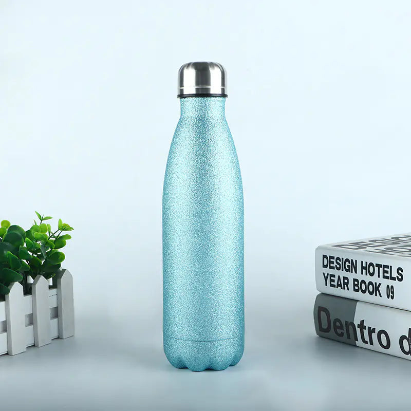 Blue durable metal sports bottle for hydration with shiny silver cap on a table with books and plant