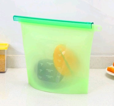 Shopi Vella silicone food storage bag in green with blue slider on kitchen counter holding sliced fruit