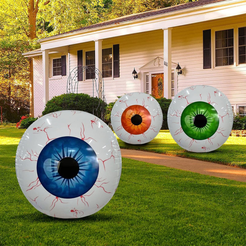 Colorful Halloween eyeball balloon decorations with blue, orange, and green irises in front of a house