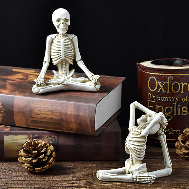 Halloween yoga skeleton decor with two small skeletons in yoga poses on books and pinecones
