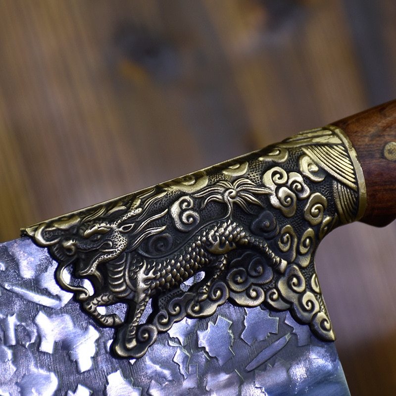 Close-up of hand-forged bone chopping knife with detailed dragon engraving and textured blade