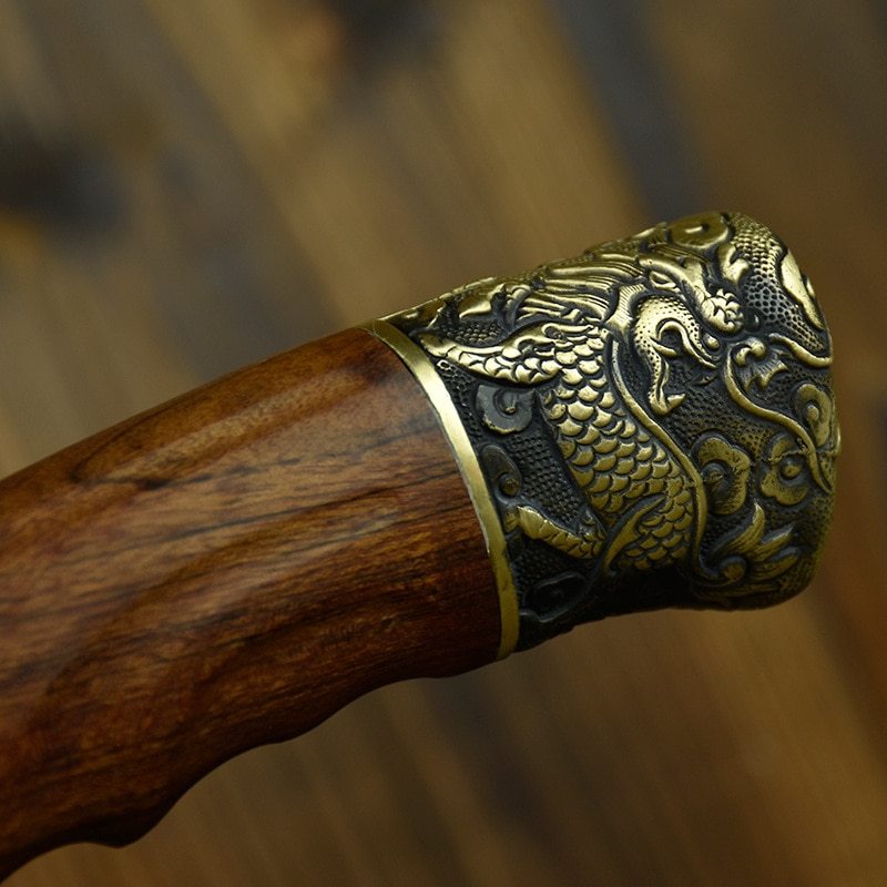 Close-up of wooden handle with intricate dragon design on hand-forged bone chopping knife