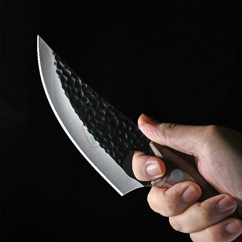Hand holding a black textured hand forged boning knife with wooden handle on black background
