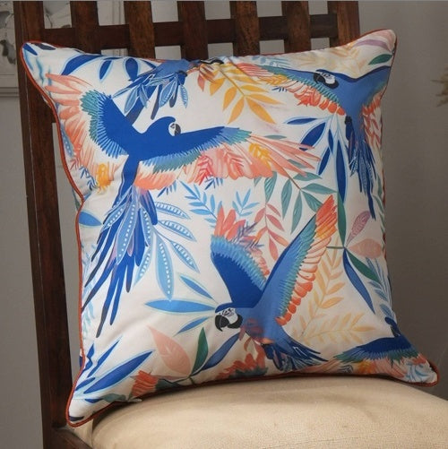 Shopi Vella hand printed decorative pillow case with blue and orange macaw design on a wooden chair