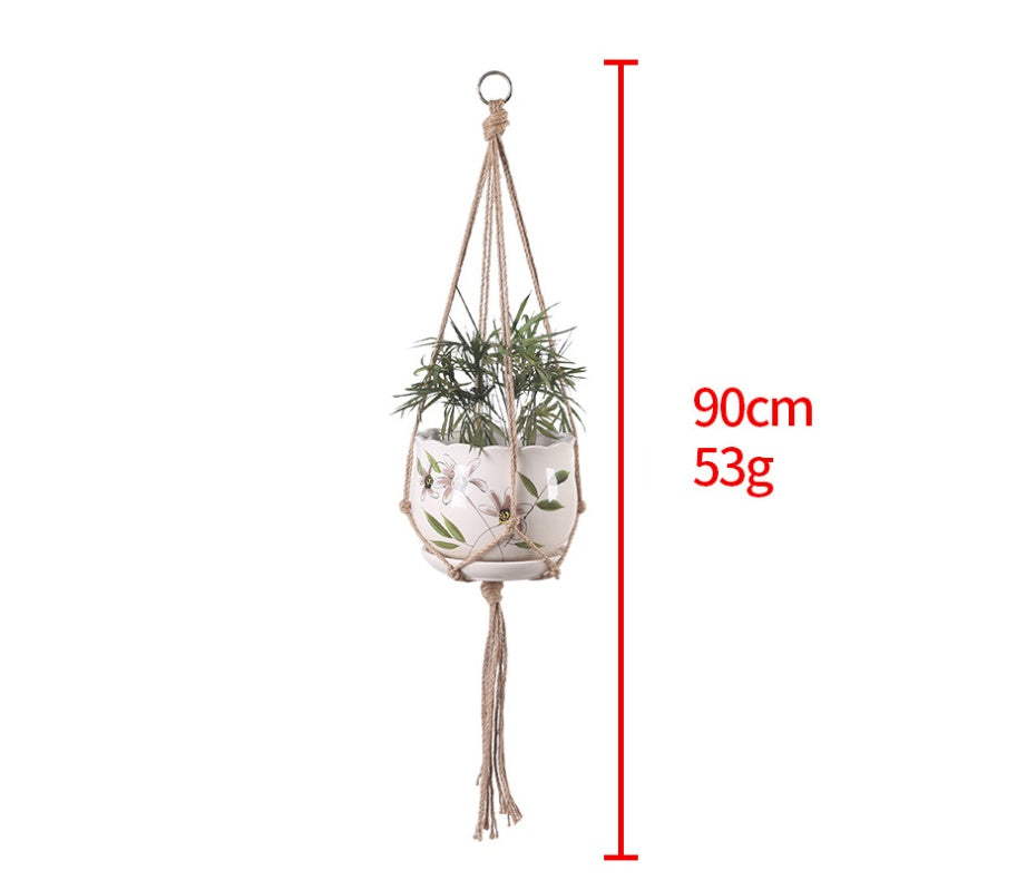 Shopi Vella hand-woven hanging basket with macrame design holding a plant in a decorative pot
