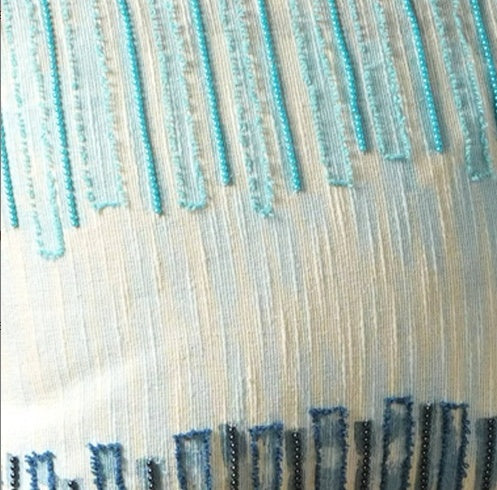 Close-up of Shopi Vella handcrafted coastal pillow case with blue and turquoise embroidered design