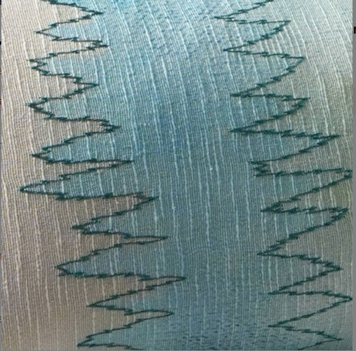 Shopi Vella handcrafted foliage pillow case with intricate zigzag stitching on a textured blue fabric