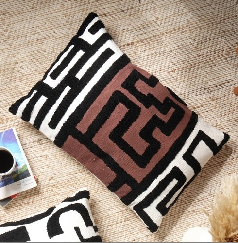 Shopi Vella handcrafted tufted lumbar pillow case with black and white geometric patterns on a beige rug