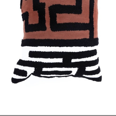 Shopi Vella handcrafted tufted lumbar pillow with black geometric patterns on brown fabric