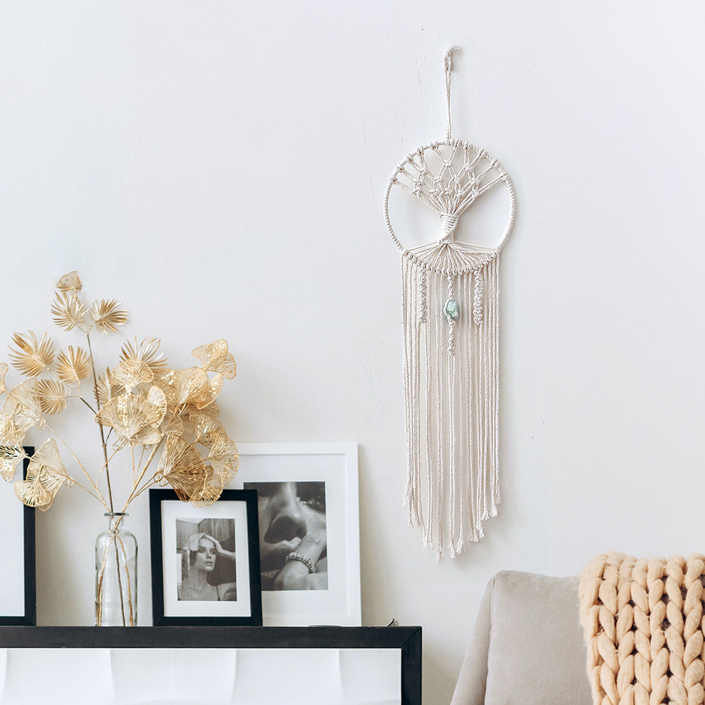 Handmade dream catcher wall hanging with intricate macrame design displayed on white wall above cozy room decor