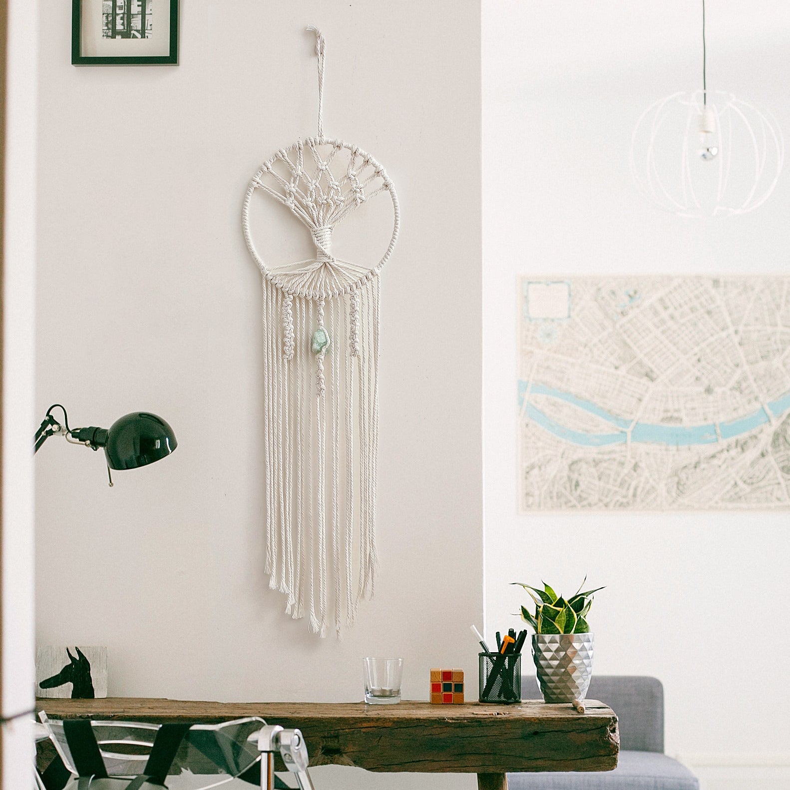 Shopi Vella handmade dream catcher wall hanging in white macrame style displayed on a living room wall above a wooden desk