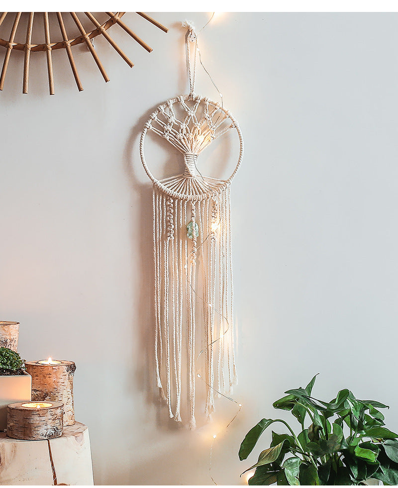 Shopi Vella handmade dream catcher wall hanging with intricate white macrame design and long tassels hanging on a white wall