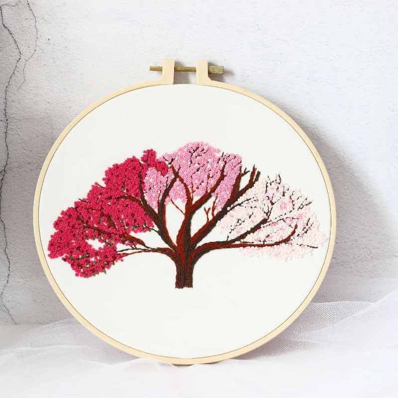 Shopi Vella handmade embroidery wall art featuring a colorful tree with pink and red blossoms in an embroidery hoop