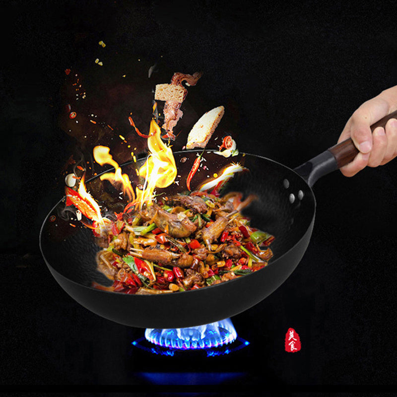 Shopi Vella handmade iron wok with stir-fried vegetables and meat over blue gas flame