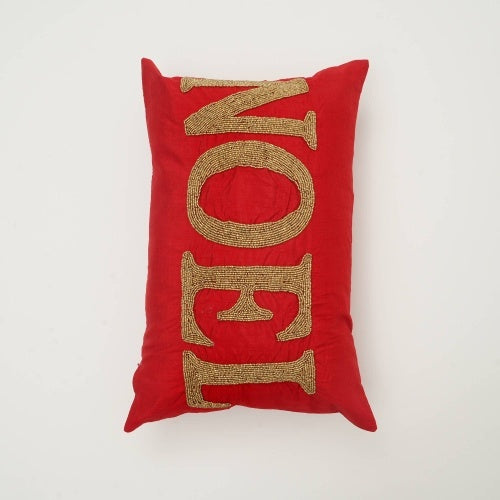 Shopi Vella handmade red Noel pillow with gold embroidered letters on a rectangular cushion