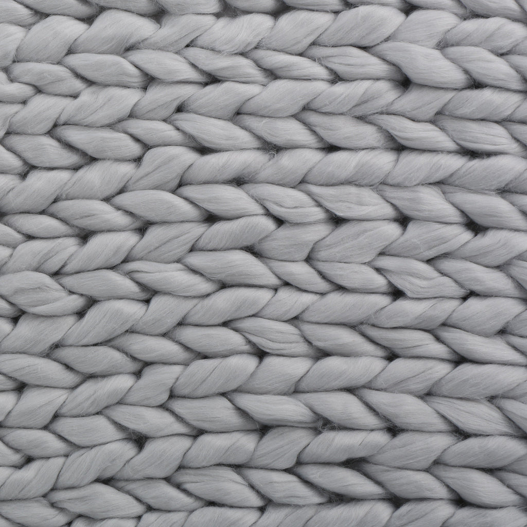 Close-up of a handwoven thick yarn blanket showing large soft yarn loops in light gray