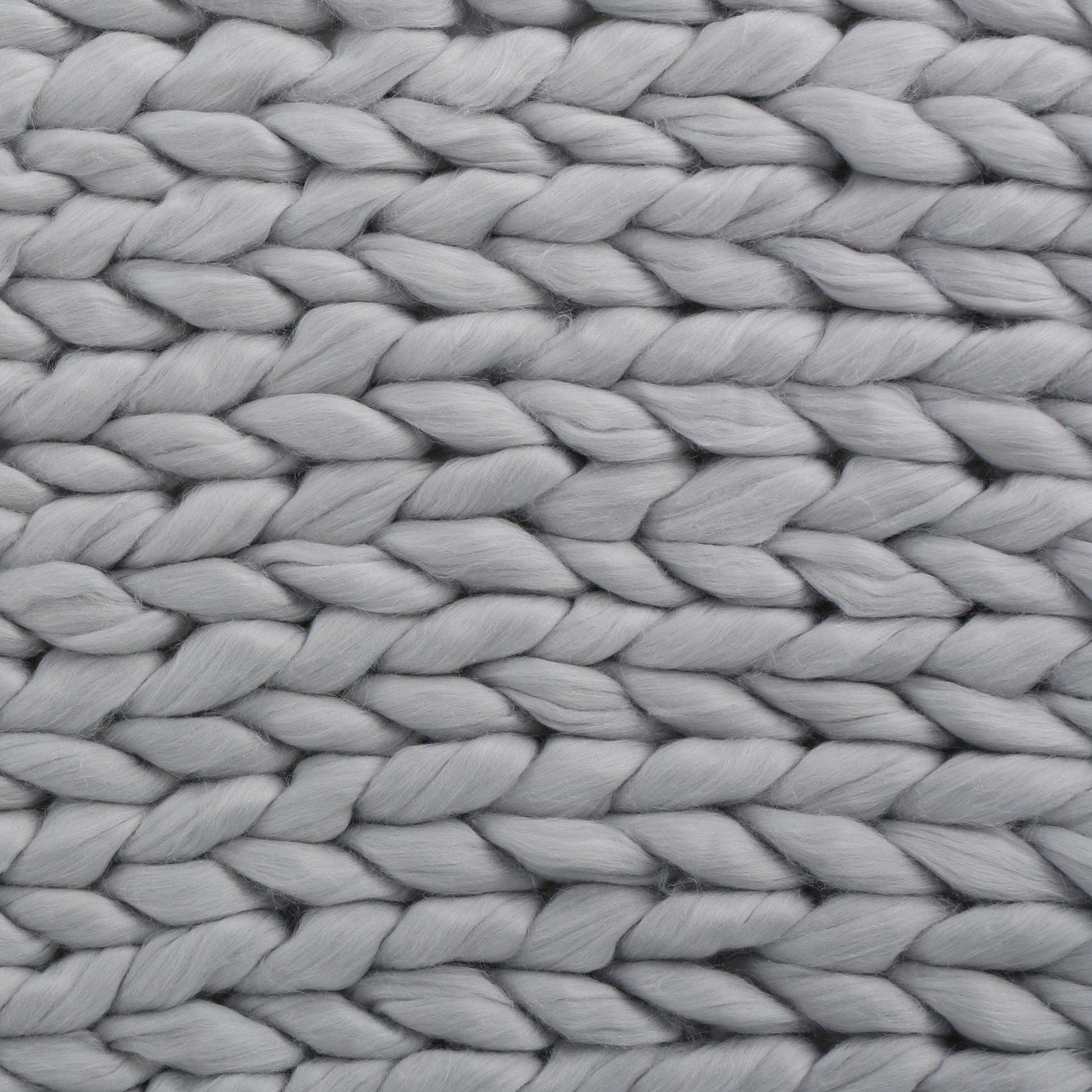 Close-up of a handwoven thick yarn blanket showing large soft yarn loops in light gray