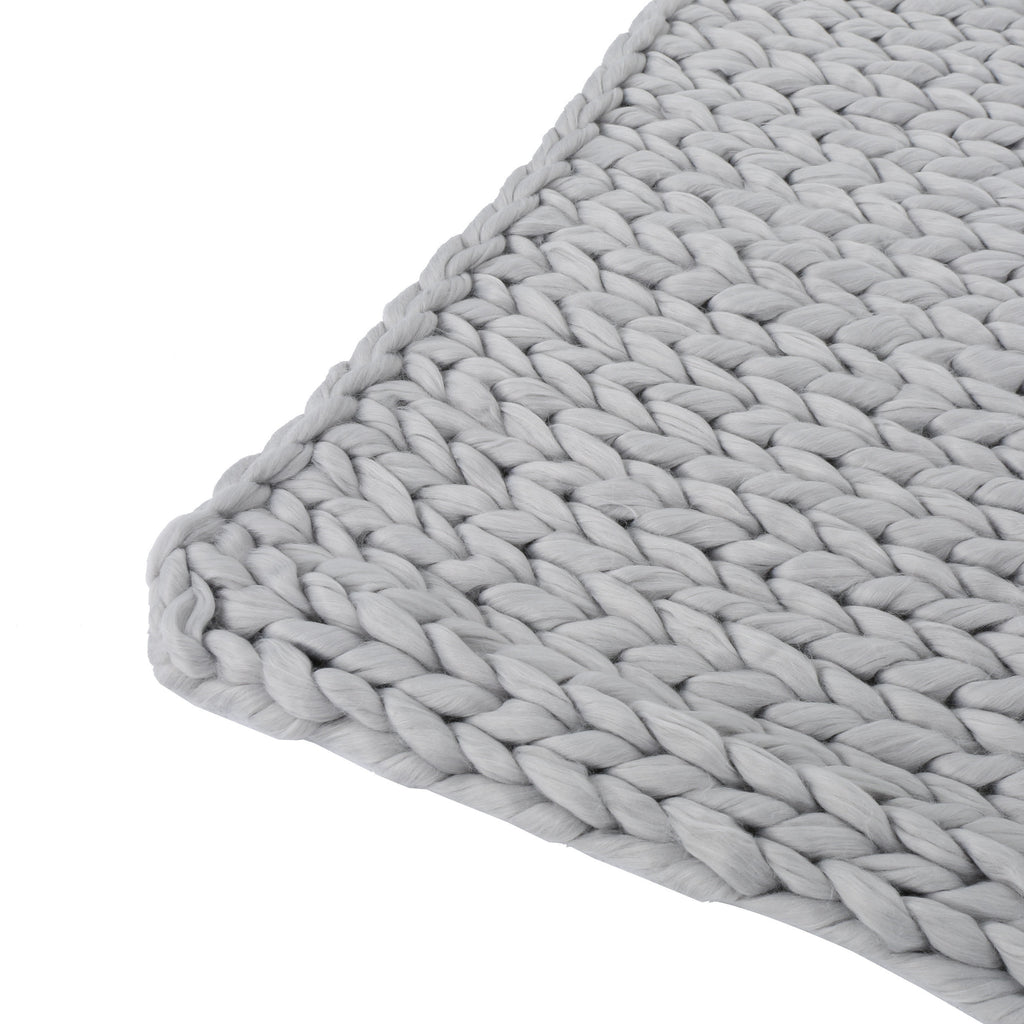 Close-up of a light gray handwoven thick yarn blanket showcasing chunky knit texture