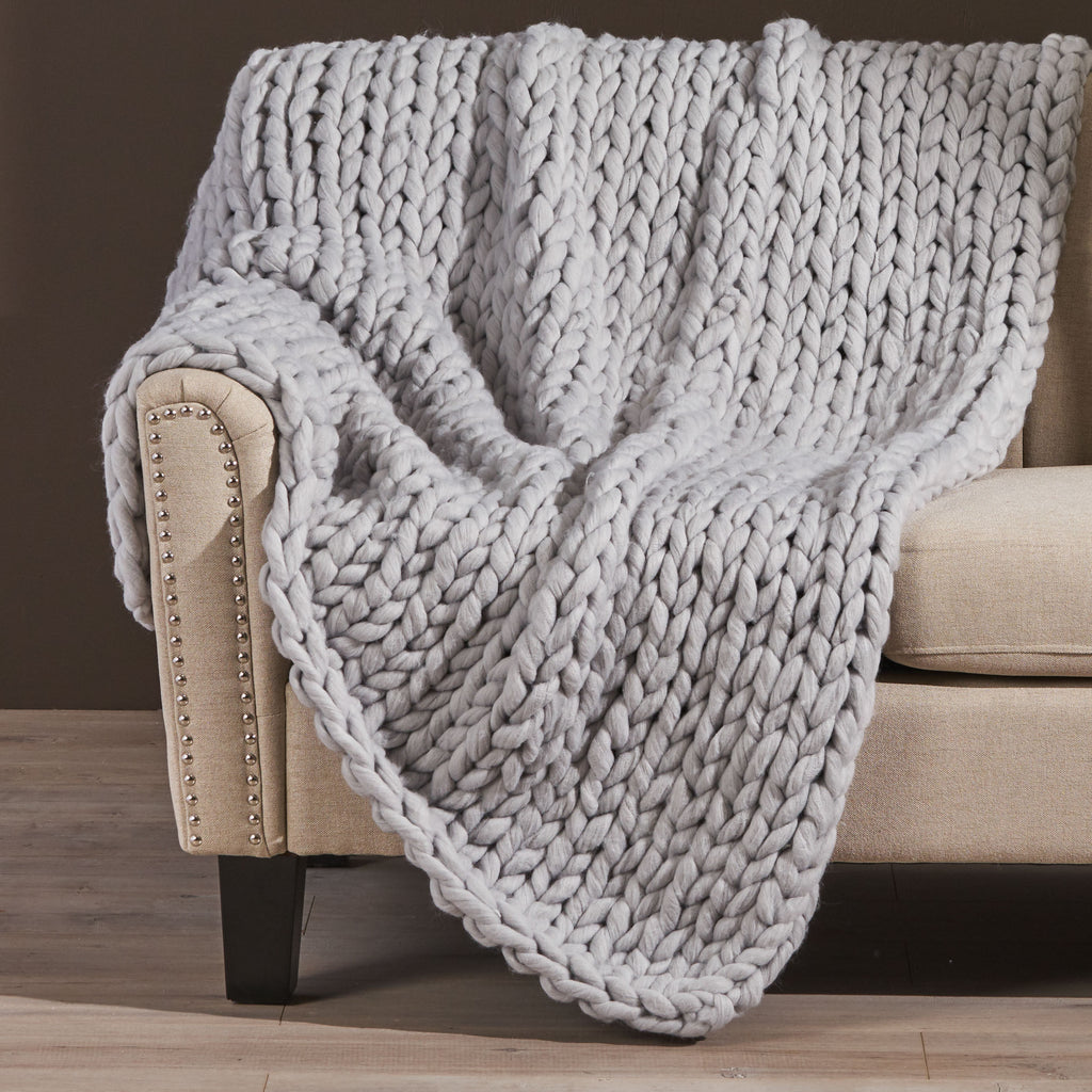 Shopi Vella handwoven thick yarn blanket draped over beige sofa armrest