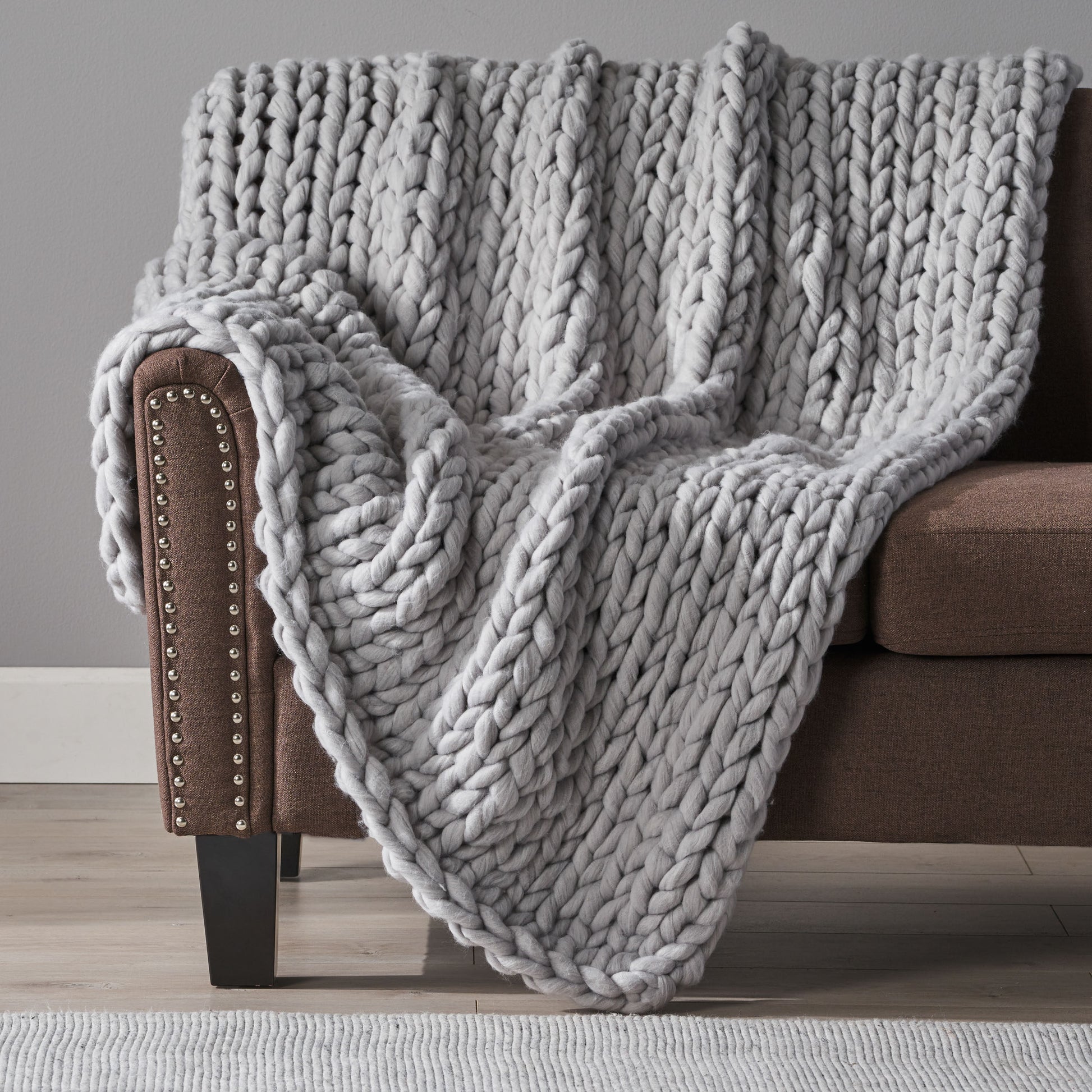 Shopi Vella bed with handwoven thick yarn blanket draped over brown sofa armrest in cozy living room