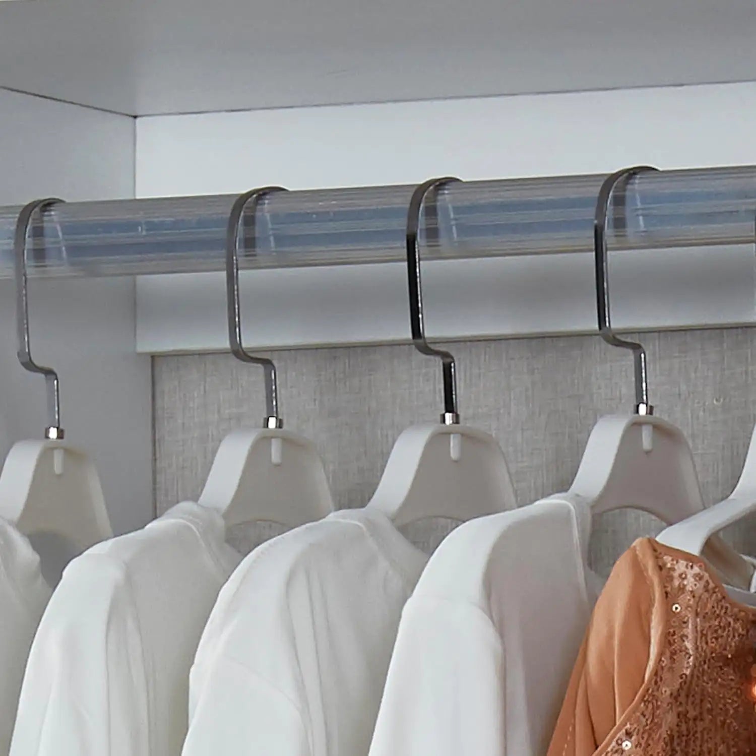 Hanging rod closet organizer for bedroom with metal hooks holding white and beige clothes