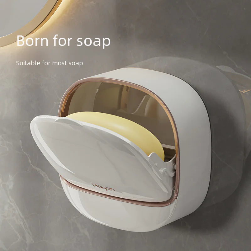 Modern wall mounted soap dish in white with a protective cover holding a bar of soap on a bathroom wall