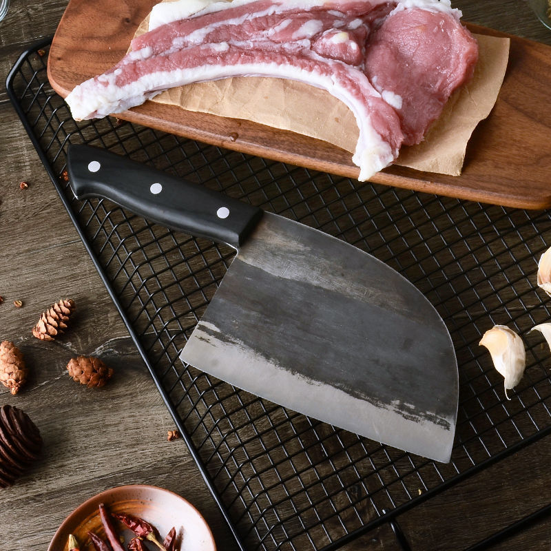 High hardness chopping knife with black handle placed on wire rack next to raw meat and garlic cloves