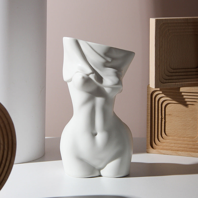 Shopi Vella human body ceramic vase in white showcasing a sculpted torso design on a modern surface