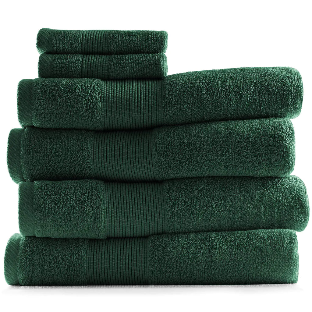 Stack of soft hunter green bathroom towels in various sizes neatly folded for bathroom use