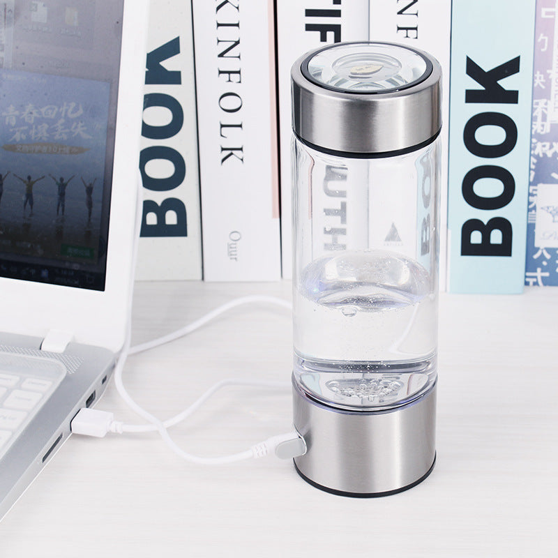 Shopi Vella hydrogen water bottle portable in clear design with stainless steel lid connected to laptop for charging