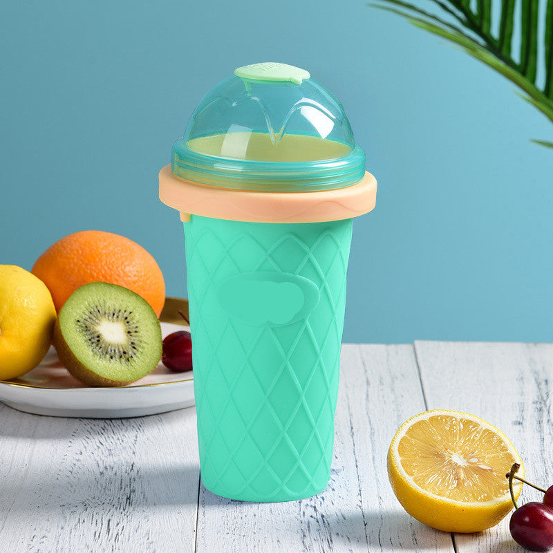 Shopi Vella instant frozen drink cup in turquoise with peach lid and clear dome top on wooden surface