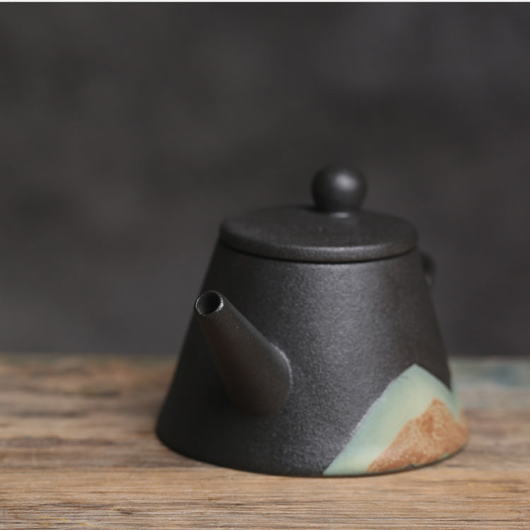 Shopi Vella Japanese ceramic teapot in black with green and brown accent on wooden surface