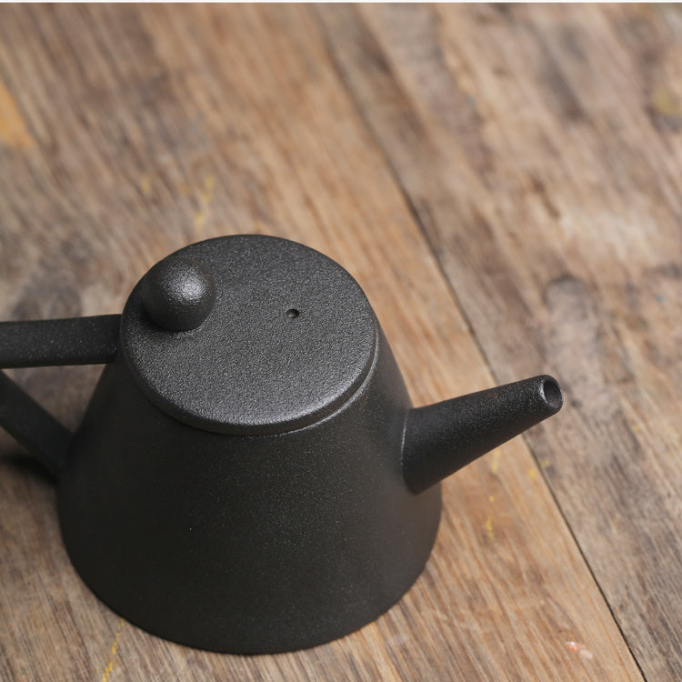Minimalist black Japanese ceramic teapot with a matte finish on wooden surface