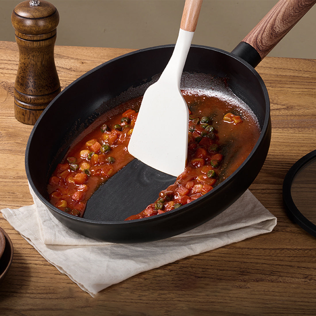 Non stick pots and pans with removable handles cooking tomato sauce with wooden spatula on wooden table