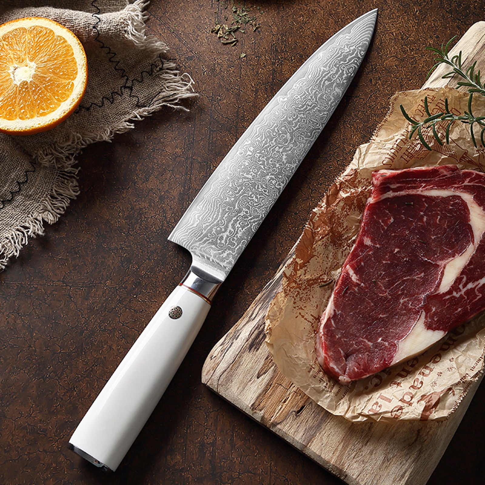Shopi Vella ultra-sharp chef knife ergonomic handle with patterned blade next to raw steak and orange slice
