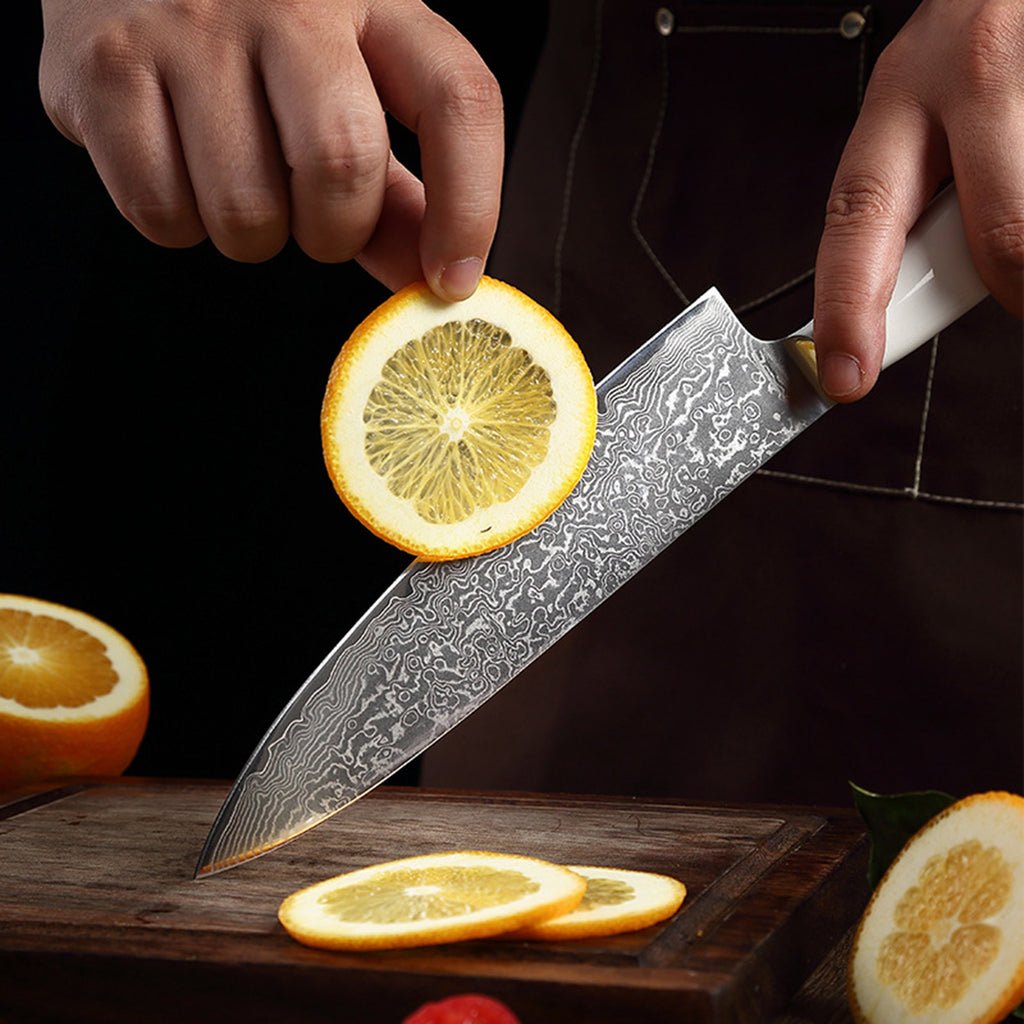 Shopi Vella ultra-sharp chef knife ergonomic handle slicing orange with detailed Damascus blade