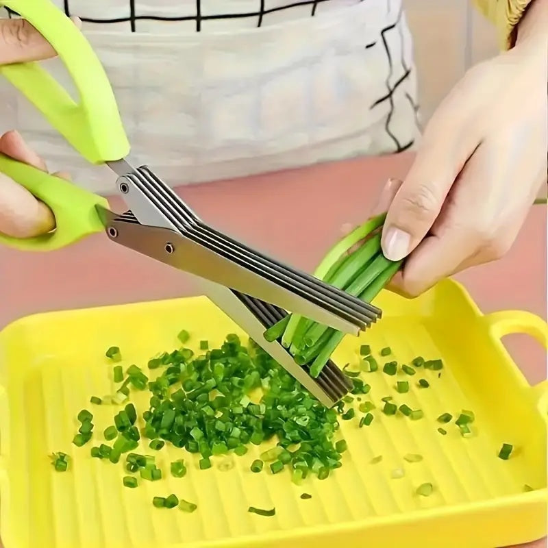 Shopi Vella 5-layer herb scissors with green handles chopping fresh herbs over yellow tray