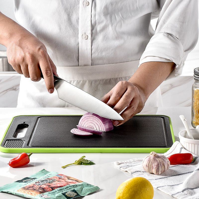 Shopi Vella kitchen chopping board with knife sharpener slicing a red onion on white countertop