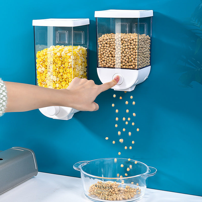Shopi Vella kitchen food storage container dispensing soybeans into a clear bowl mounted on blue wall