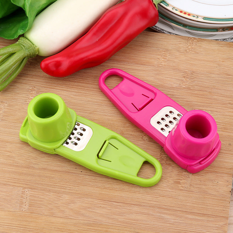 Shopi Vella garlic masher kitchen tool in green and pink with stainless steel grater on wooden cutting board