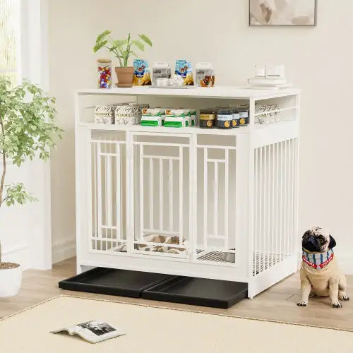 White large wooden dog kennel furniture with storage shelves and two black trays, next to a small dog indoors