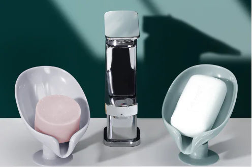 Gray leaf shaped soap holder with pink soap and gray leaf shaped soap holder with white soap on white surface