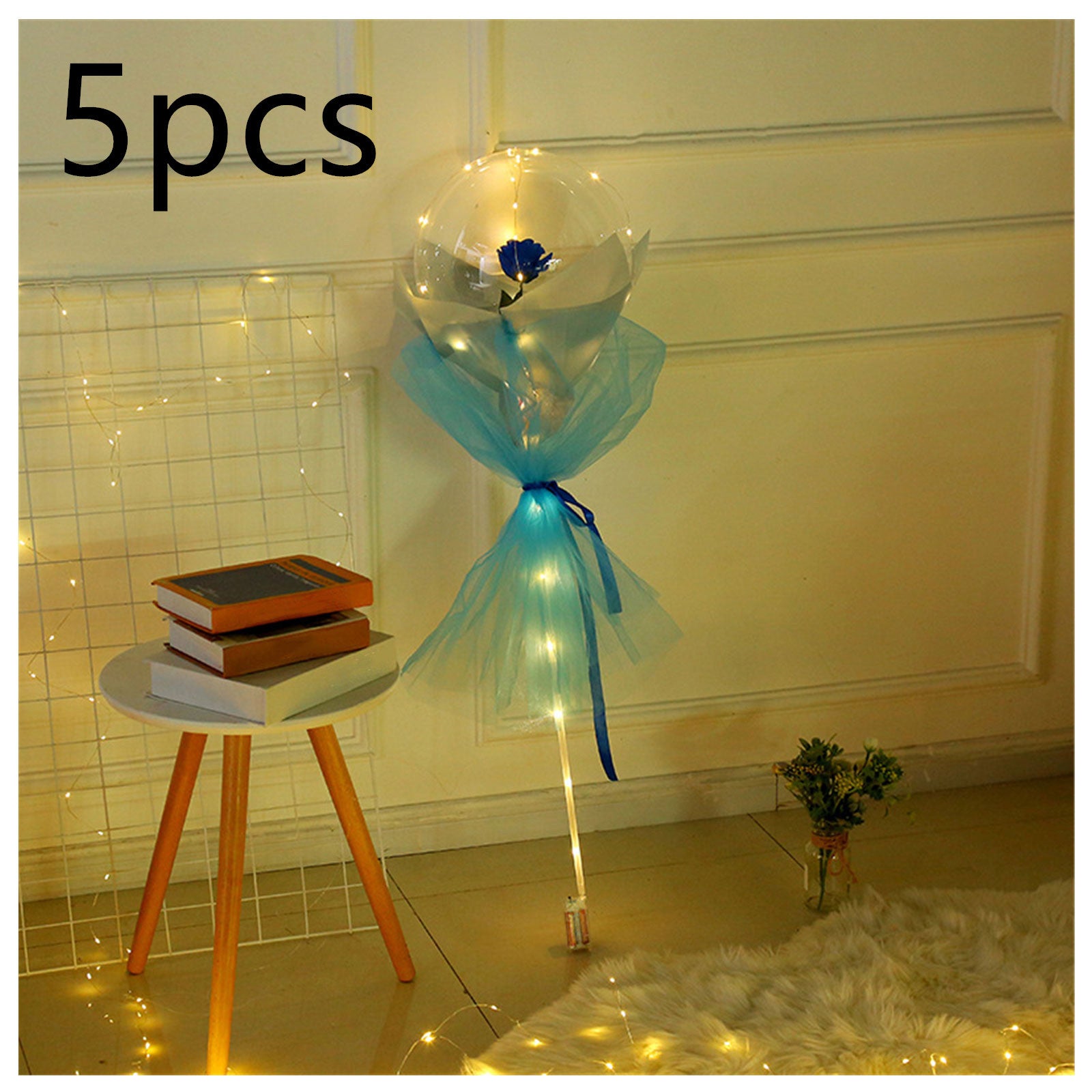 LED rose balloon bouquet with blue rose and decorative lights next to small wooden table and books