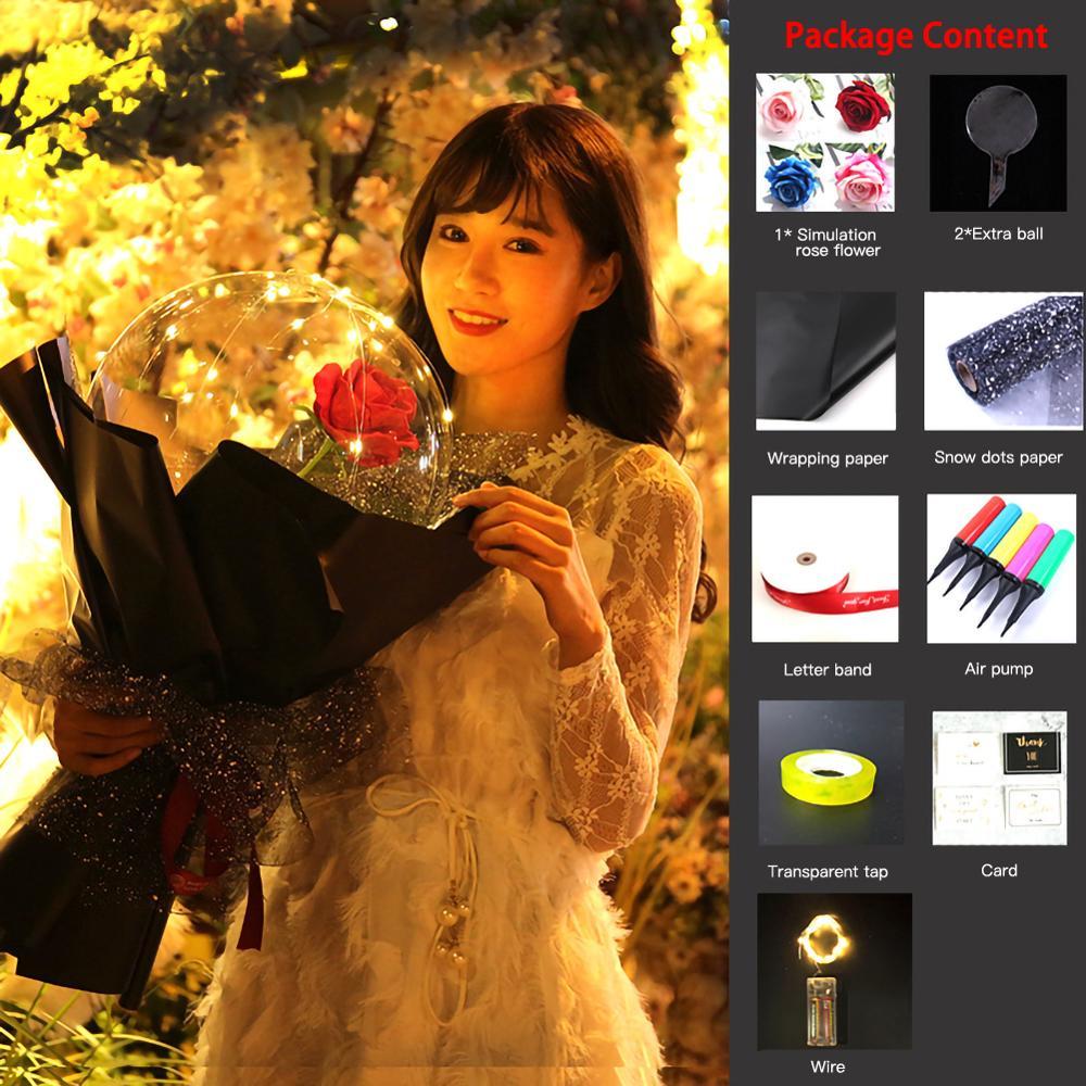 Woman holding LED rose balloon bouquet with a red rose encased in a clear balloon wrapped in black paper