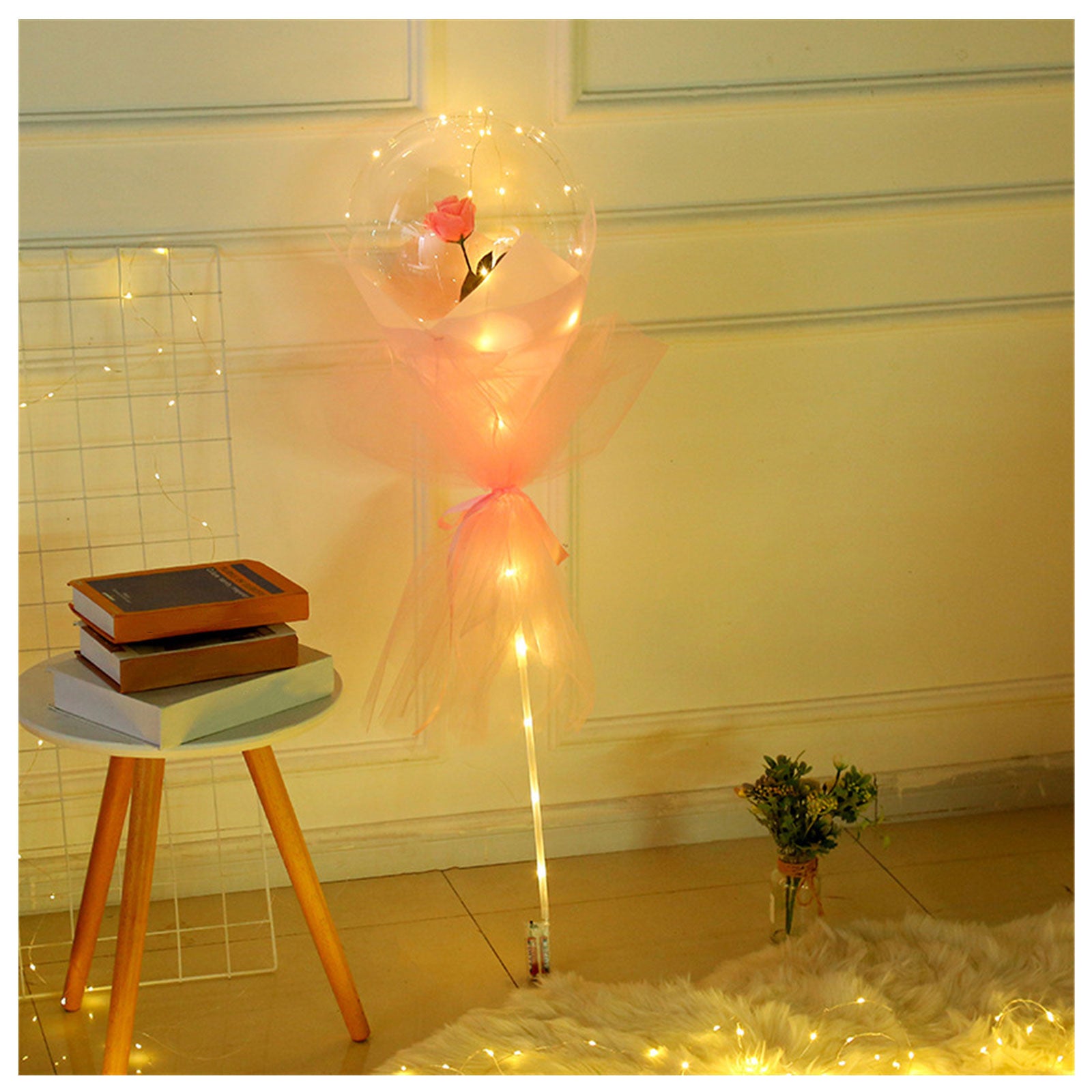 Shopi Vella LED rose balloon bouquet glowing softly next to a white round table with books in cozy home storage setup