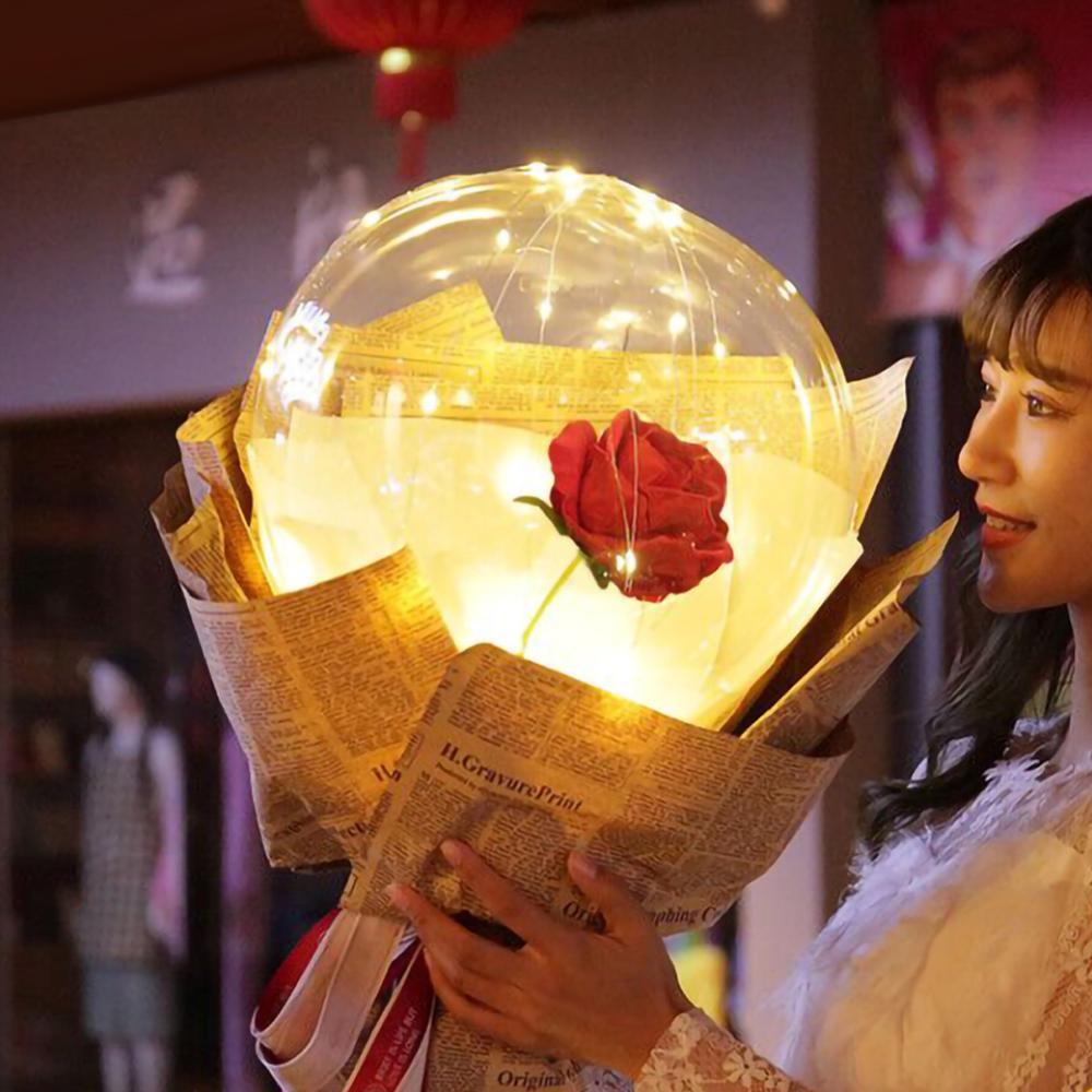 Shopi Vella LED rose balloon bouquet with glowing lights wrapped in newspaper held by a woman