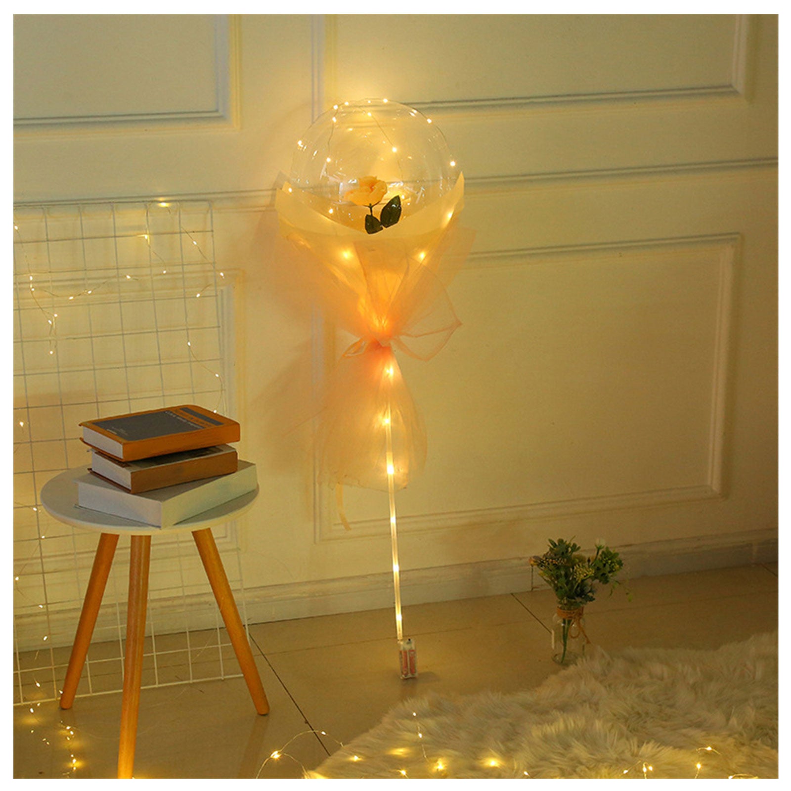 LED rose balloon bouquet glowing with warm lights next to a small table with books in cozy room