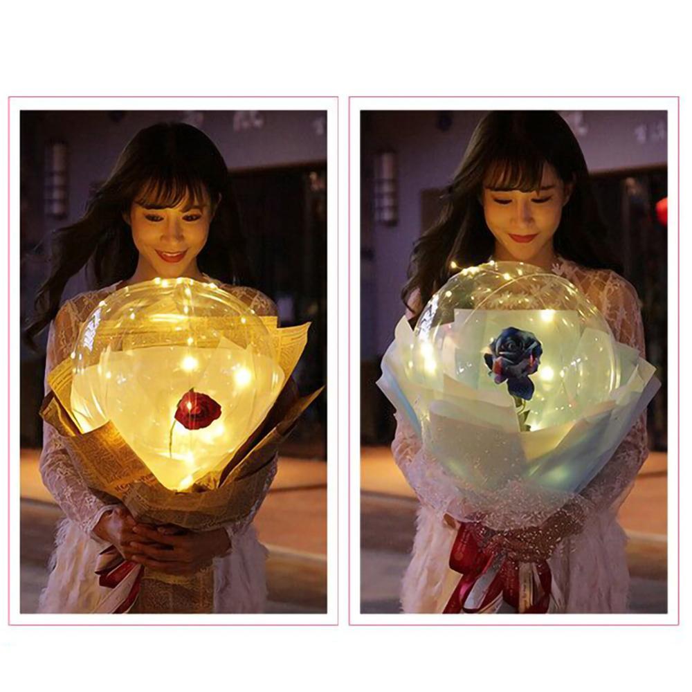 Woman holding Shopi Vella LED rose balloon bouquet glowing softly in dark with decorative wrapping